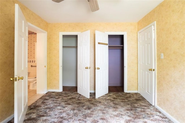 unfurnished bedroom featuring multiple closets, carpet floors, and ceiling fan