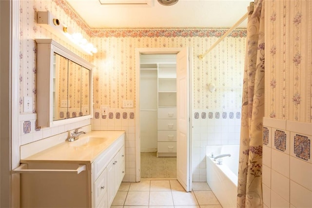 bathroom with tile patterned flooring, tile walls, a tub, and vanity