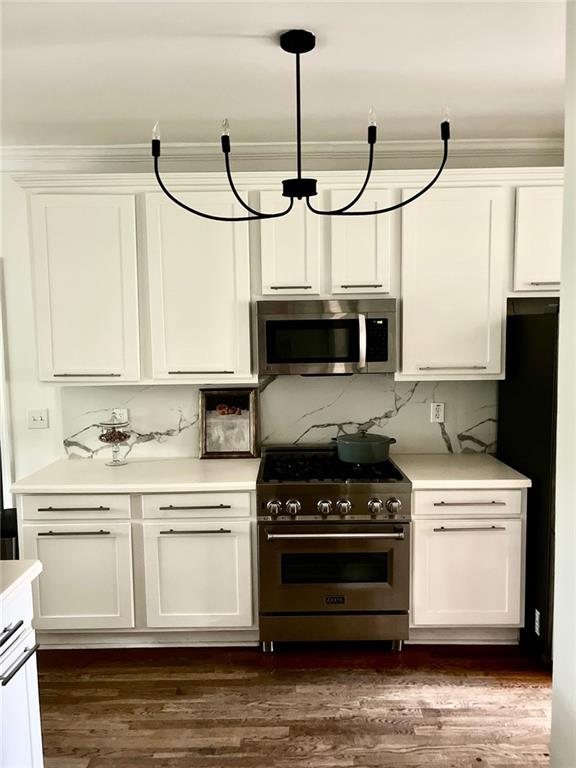 8525 Anchor On Lanier Ct, Gainesville, GA 30506 - kitchen with stainless steel appliances, white cabinets, light countertops, backsplash, and ornamental molding