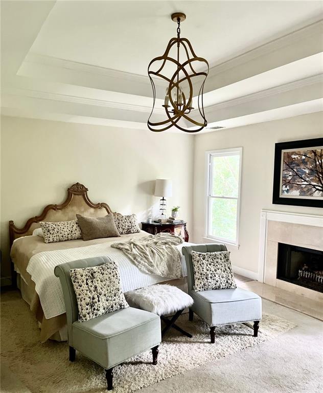 8525 Anchor On Lanier Ct, Gainesville, GA 30506 - carpeted bedroom featuring ornamental molding, a raised ceiling, a tile fireplace, a chandelier, and baseboards