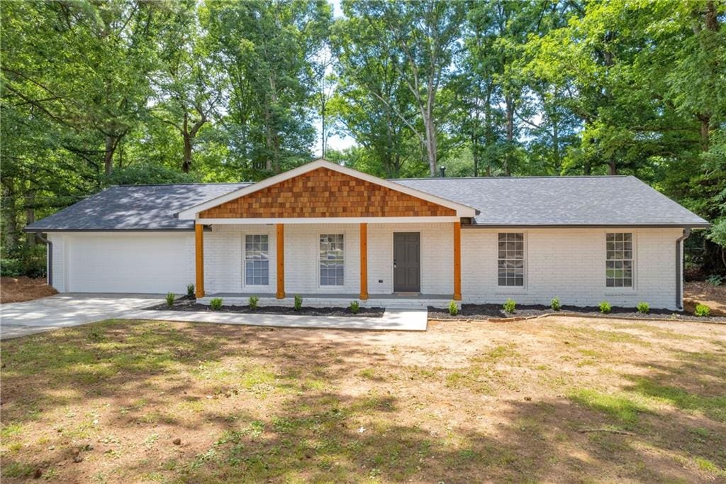 single story home featuring a garage, a front lawn, and covered porch