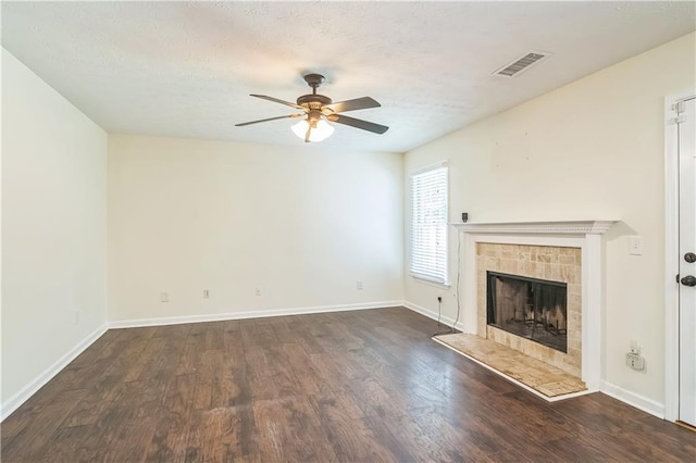 unfurnished living room with ceiling fan, dark wood finished floors, a fireplace, baseboards, and a textured ceiling