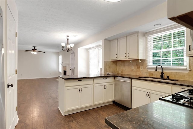 kitchen featuring stainless steel dishwasher, a sink, a peninsula, dark wood-type flooring, and backsplash