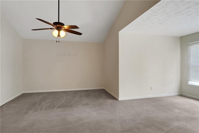 carpeted empty room with ceiling fan, baseboards, and vaulted ceiling