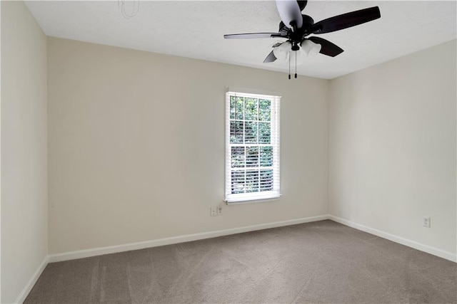 carpeted spare room featuring baseboards and ceiling fan
