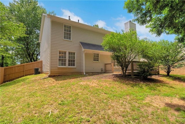 rear view of house with cooling unit, a deck, and a chimney