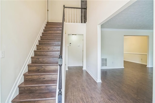 stairway featuring wood finished floors, baseboards, and ornamental molding