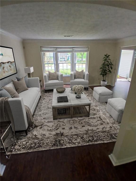 living area featuring crown molding, wood finished floors, baseboards, and a textured ceiling