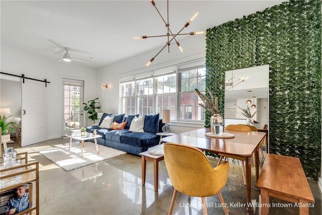 living room featuring ceiling fan with notable chandelier, concrete flooring, and a barn door