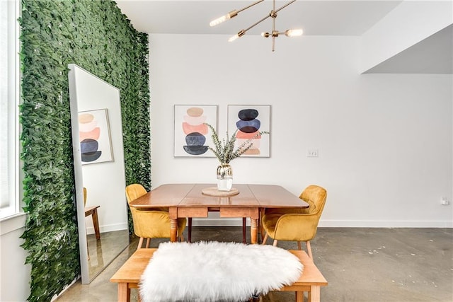 dining room featuring a notable chandelier, baseboards, and concrete flooring