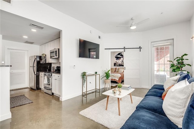 living room with a barn door, concrete floors, visible vents, and baseboards