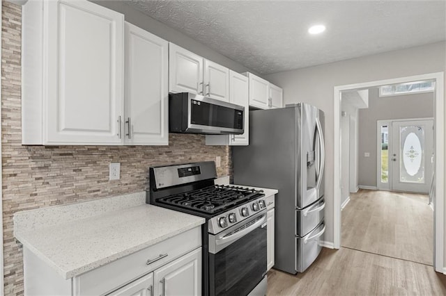 kitchen featuring light hardwood / wood-style floors, white cabinetry, stainless steel appliances, and light stone counters