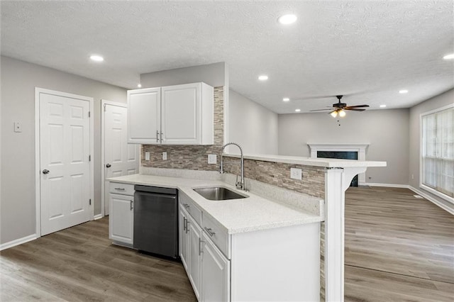 kitchen featuring white cabinets, a breakfast bar, dishwashing machine, wood-type flooring, and sink