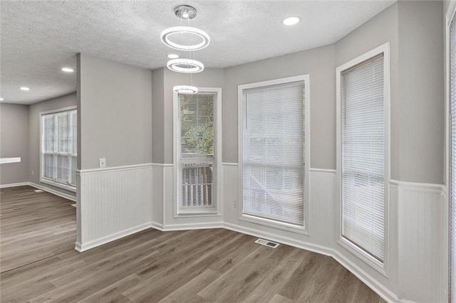 unfurnished dining area with a textured ceiling and wood-type flooring