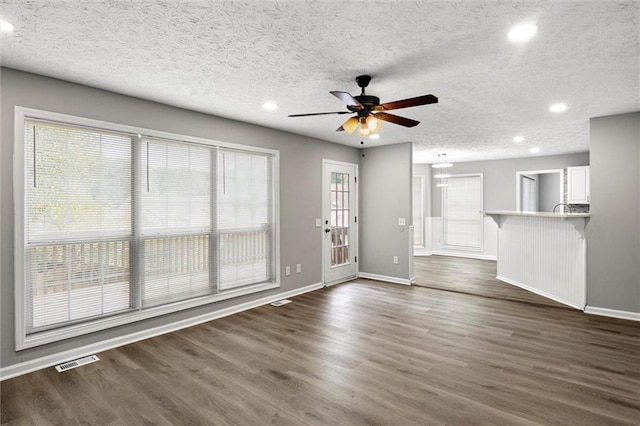 unfurnished living room featuring dark hardwood / wood-style flooring, a textured ceiling, and plenty of natural light