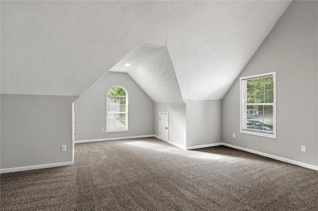 bonus room featuring a textured ceiling, vaulted ceiling, and dark carpet