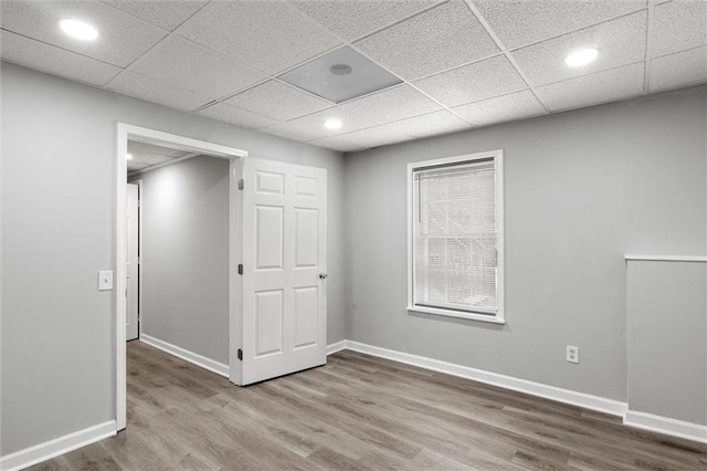 empty room with a drop ceiling and wood-type flooring