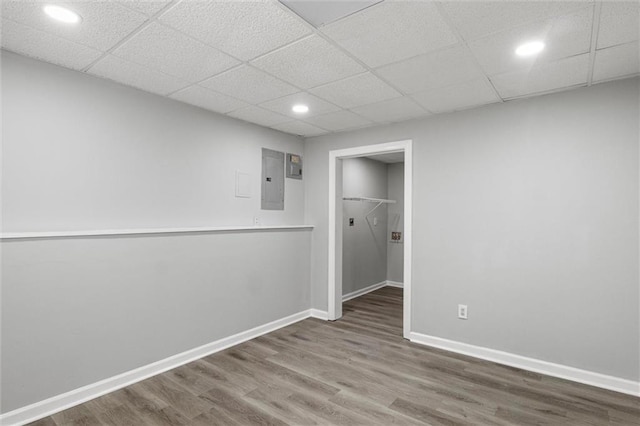 unfurnished bedroom featuring a closet, a paneled ceiling, electric panel, and hardwood / wood-style floors