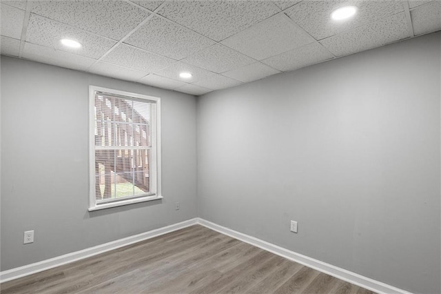 spare room with a drop ceiling and hardwood / wood-style floors