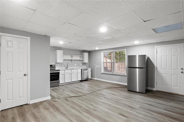 kitchen featuring light hardwood / wood-style flooring, stainless steel appliances, sink, white cabinetry, and a paneled ceiling