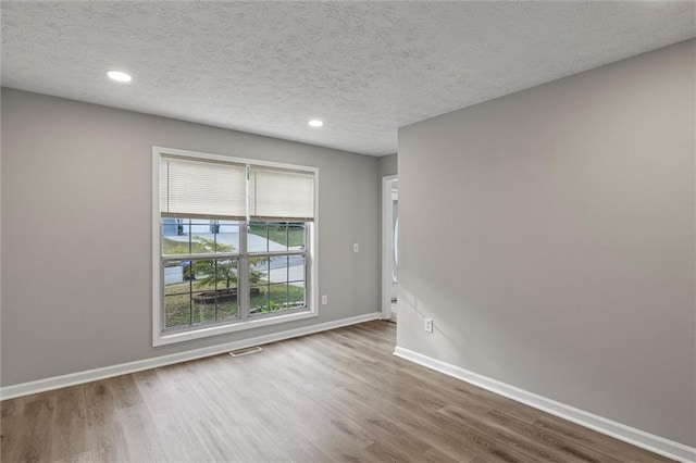 spare room featuring a textured ceiling and hardwood / wood-style floors