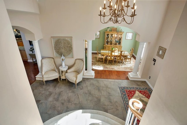 dining room with arched walkways, decorative columns, a chandelier, a high ceiling, and baseboards