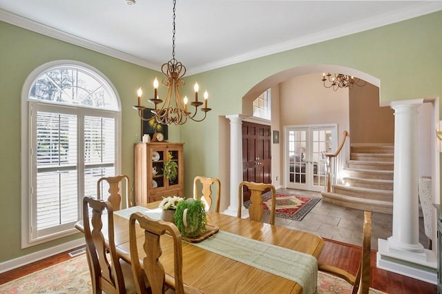 dining space featuring french doors, arched walkways, a chandelier, and ornamental molding