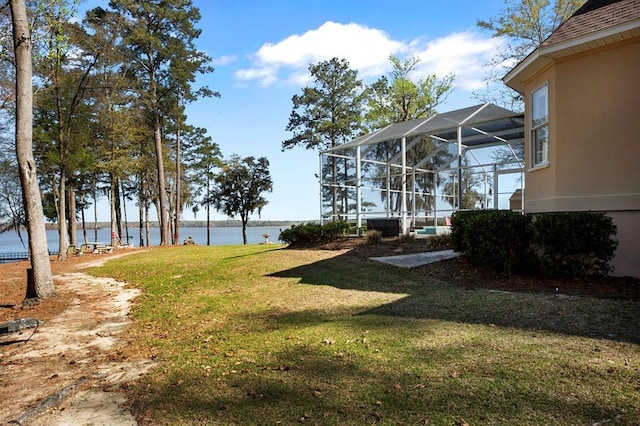 view of grassy yard with a water view and glass enclosure
