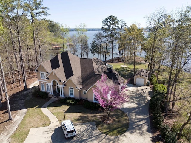 view of front of house with a water view, a garage, roof with shingles, stucco siding, and concrete driveway