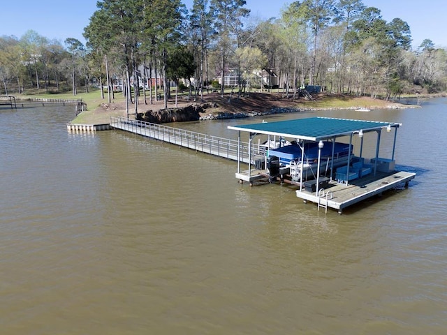 dock area featuring boat lift, a water view, and view of wooded area
