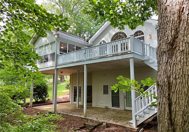 rear view of property with a deck, a patio area, and a sunroom