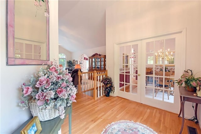 interior space featuring a chandelier, wood-type flooring, high vaulted ceiling, and french doors