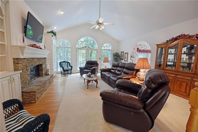 living room featuring ceiling fan, light hardwood / wood-style floors, a stone fireplace, and lofted ceiling