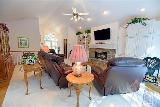 living room with a fireplace, light wood-type flooring, ceiling fan, and lofted ceiling