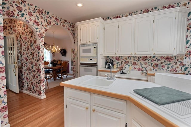 kitchen featuring white cabinets, sink, and a chandelier