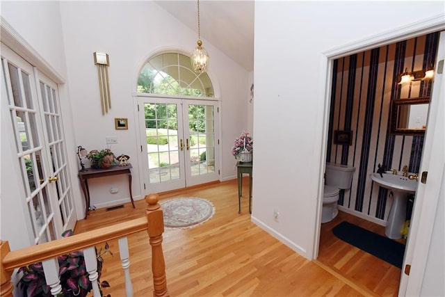 doorway to outside with french doors, sink, vaulted ceiling, a notable chandelier, and wood-type flooring