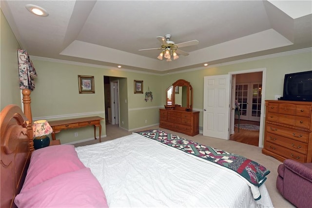 bedroom with ceiling fan, a raised ceiling, light carpet, and crown molding