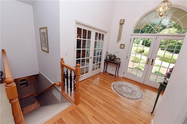 entryway with french doors, hardwood / wood-style floors, a high ceiling, and a notable chandelier