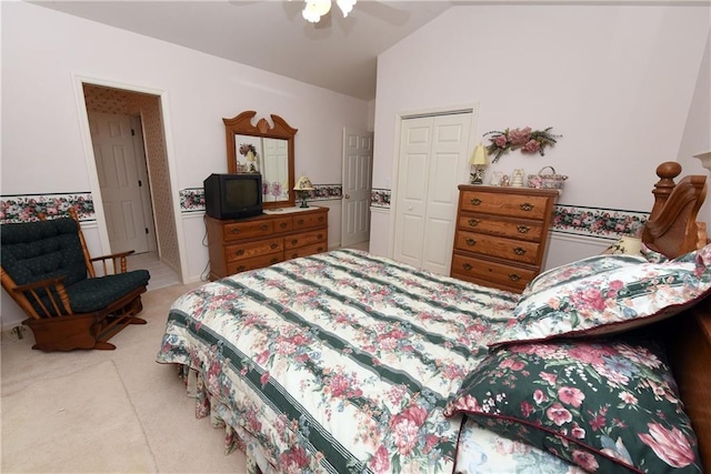 bedroom featuring ceiling fan, a closet, light colored carpet, and lofted ceiling