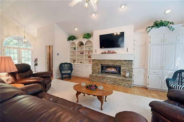 living room with ceiling fan, light hardwood / wood-style floors, lofted ceiling, and a fireplace