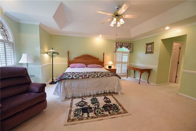 bedroom with ceiling fan, a raised ceiling, ornamental molding, and light carpet