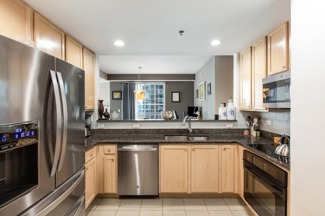 kitchen featuring tasteful backsplash, a sink, black appliances, and light brown cabinetry