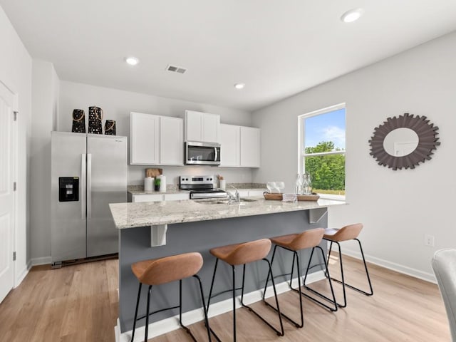 414 Oak View Ln, Dallas, GA 30157 - kitchen with stainless steel appliances, a breakfast bar area, light wood-type flooring, white cabinetry, and recessed lighting