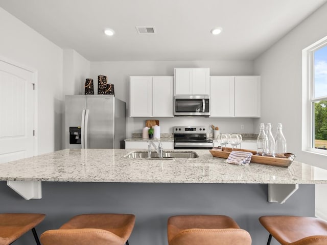 414 Oak View Ln, Dallas, GA 30157 - kitchen with stainless steel appliances, white cabinets, light stone counters, recessed lighting, and a breakfast bar area
