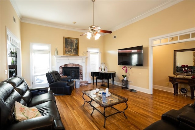 living room with a brick fireplace, crown molding, ceiling fan, and hardwood / wood-style flooring