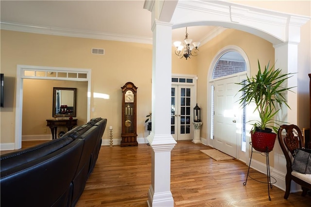 entrance foyer with crown molding, wood finished floors, decorative columns, and visible vents