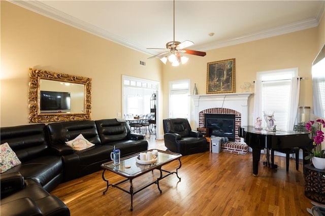 living area featuring crown molding, ceiling fan, wood finished floors, and a fireplace