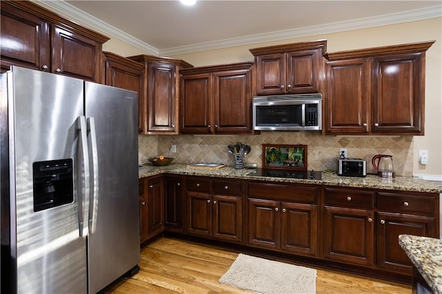 kitchen featuring light wood-style flooring, tasteful backsplash, light stone counters, and stainless steel appliances