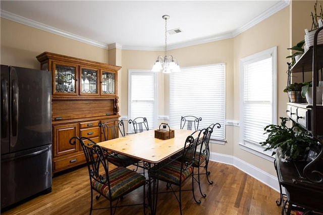 dining room featuring crown molding, visible vents, a chandelier, and dark wood finished floors