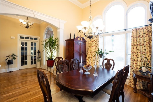 dining room with french doors, an inviting chandelier, ornamental molding, and wood finished floors